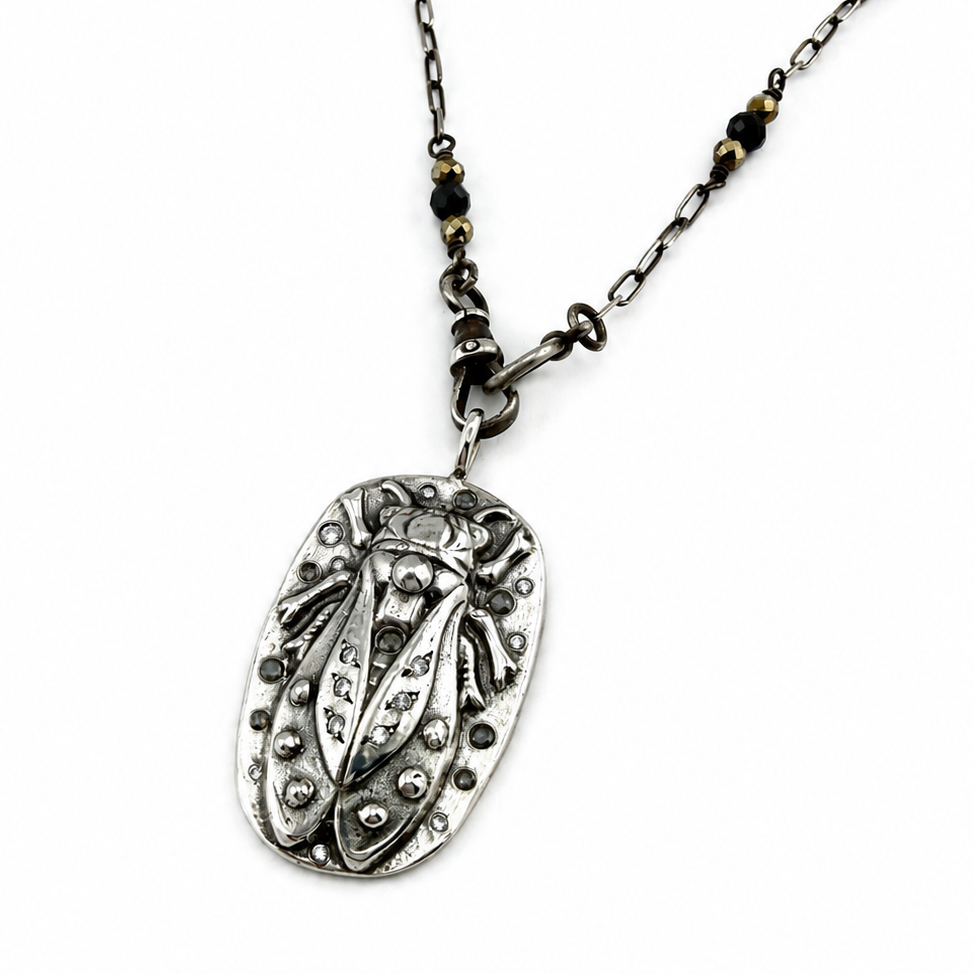 
                  
                    An antique silver beetle pendant necklace on a matching chain with small black and gold beads, shown against a plain white background.
                  
                